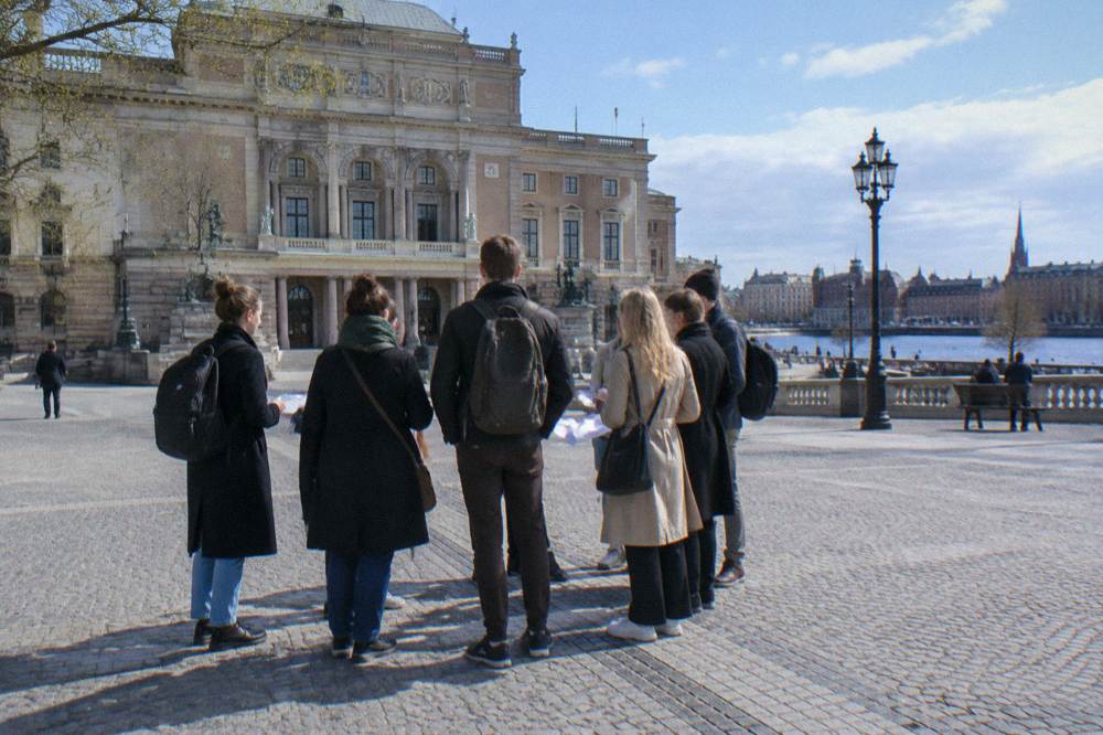 A guided walking tour group standing in a cobblestone square in Stockholm's Old Town