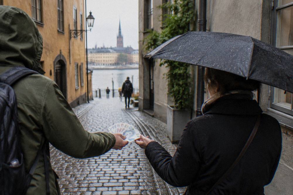 A visitor handing krona banknotes to a tour guide at the end of a walking tour on a Stockholm street