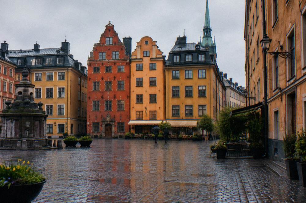 Cobblestone street in Gamla Stan with colorful 17th century buildings and a church spire in the background