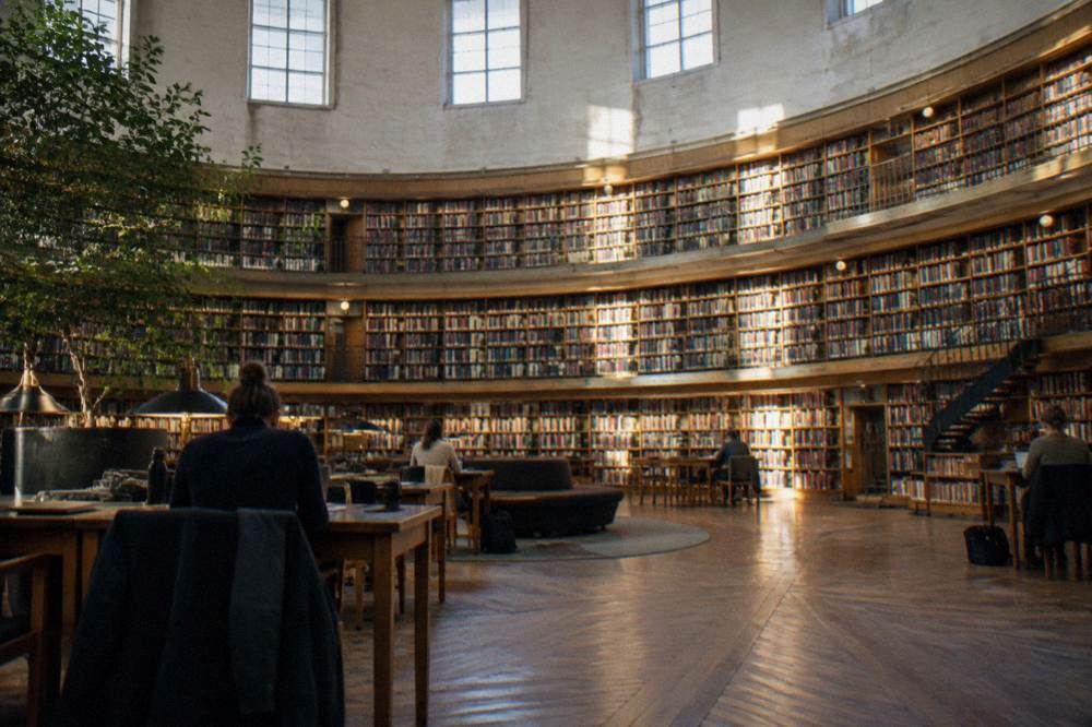 Visitors reading in the rotunda of Stockholm Public Library under its tall curved bookshelves