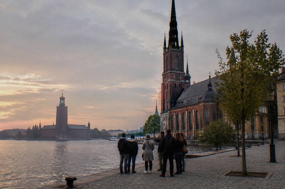 A guided walking group stopped on cobblestones in front of old Stockholm buildings