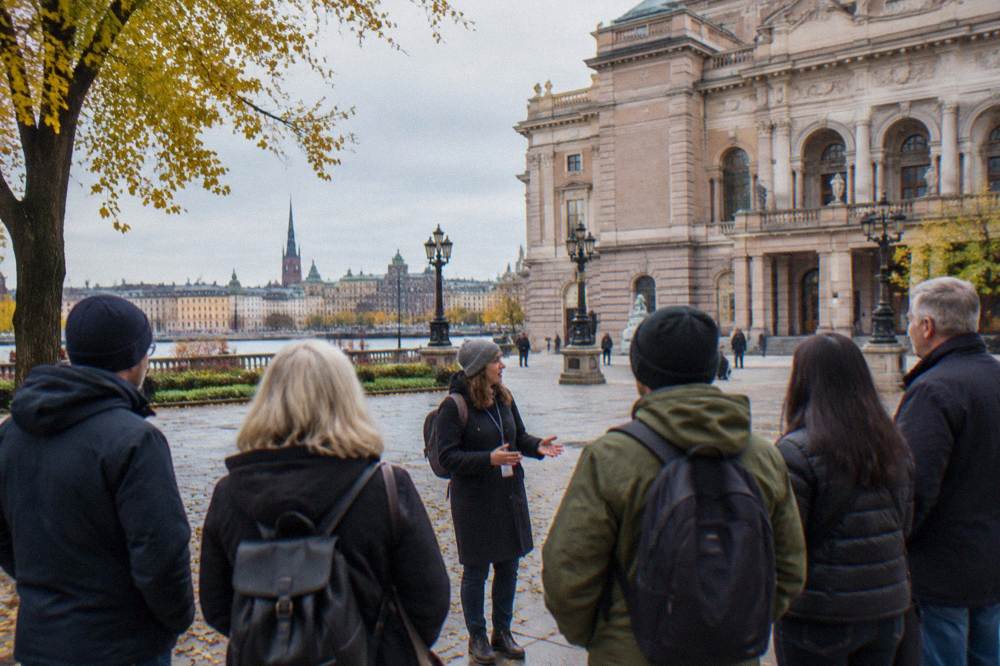 A guided group of walkers standing in a cobbled square among colourful old town buildings