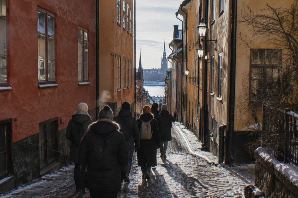 A small tour group following a guide down a narrow lane of coloured old buildings in Stockholm's Old Town